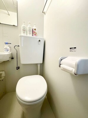 A small, clean bathroom with a toilet, a sink, and a toilet paper holder. - LunaStay Apartments - 103 (東京)