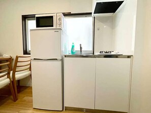 A compact kitchenette with a microwave, a refrigerator, a sink, and a stove. - LunaStay Apartments - 103 (東京)