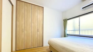 Quarto com guarda-roupa de madeira, cama e janela com cortinas.