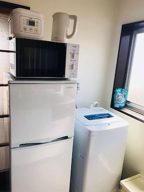 Eine kleine Küche mit Mikrowelle, Kühlschrank und Waschmaschine.