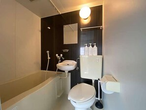 Ein modernes Badezimmer mit Badewanne, Toilette, Waschbecken und Spiegel.