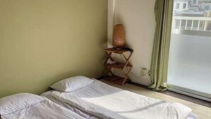 A room with two beds, a small table with a lamp, and a window with a view of buildings. - LunaStay Apartments - 301 (東京)