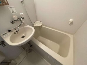 Une salle de bain équipée d’un lavabo, d’une baignoire, d’un sèche-mains et d’un distributeur de savon.