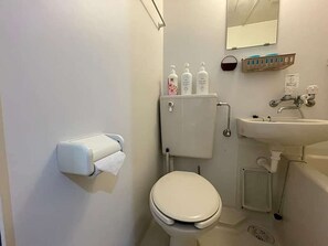 Ein Badezimmer mit Toilette, Waschbecken und einem Händetrockner.