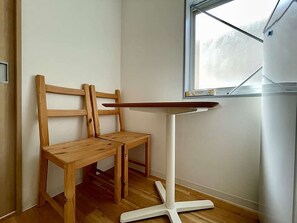 A corner room with a wooden bench, a white table with a wooden top, and a window. - LunaStay Apartments - 203 (東京)