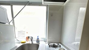Ett kompakt kök med en diskho, en gasspis och ett fönster som släpper in naturligt ljus.