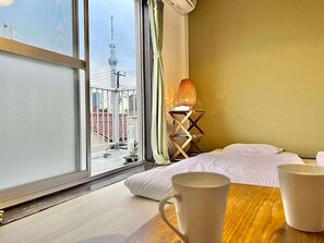 A hotel room with a large window, a bed, a bedside table with two cups, and a lamp. - LunaStay Apartments - 302 (東京)