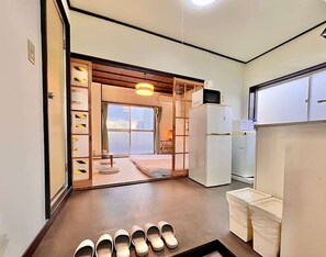 A hotel room with a sliding door leading to a balcony, a refrigerator, and a set of slippers on the floor. - LunaStay Apartments - 302 (東京)