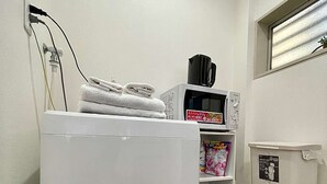 Una cocina compacta con un refrigerador blanco, un microondas y un estante con productos envasados.