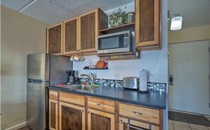 Eine Küche mit Holzausstattung, einem Edelstahl-Kühlschrank, einer Mikrowelle und einem Spülbecken mit Armatur.