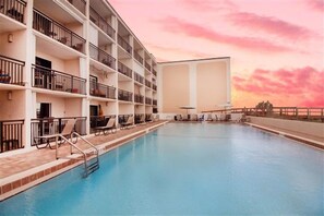 Ein Hotel mit Schwimmbad, mehreren Balkonen und Blick auf den Sonnenuntergang.