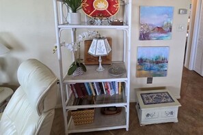 Ein weißes Metallregal mit Dekorationsobjekten, Büchern und einem kleinen, weißen Schrank mit blauen Mustern.