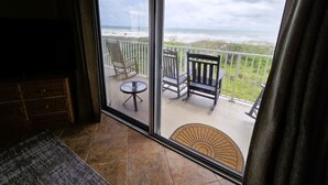 A balcony with a view of the ocean, a chair, a small table, and a doormat. - Beachfront Ocean-Views Condo, Balcony! Pool, BBQ (St. Augustine Beach)