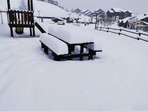 A snow-covered outdoor area with a wooden bench and a picnic table. - Apartment for 2 to 6 people at the base of the slopes (Saint-Jean-d'Aulps)
