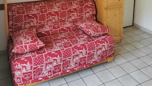 Ein Zimmer mit einem Holzschrank, einem roten Sofa mit Muster und einem Fliesenboden.