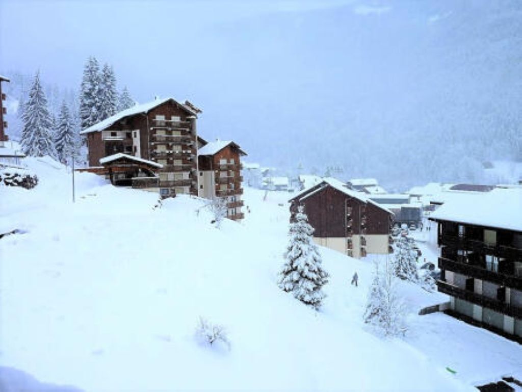 A snow-covered mountain village with wooden buildings and a ski slope.