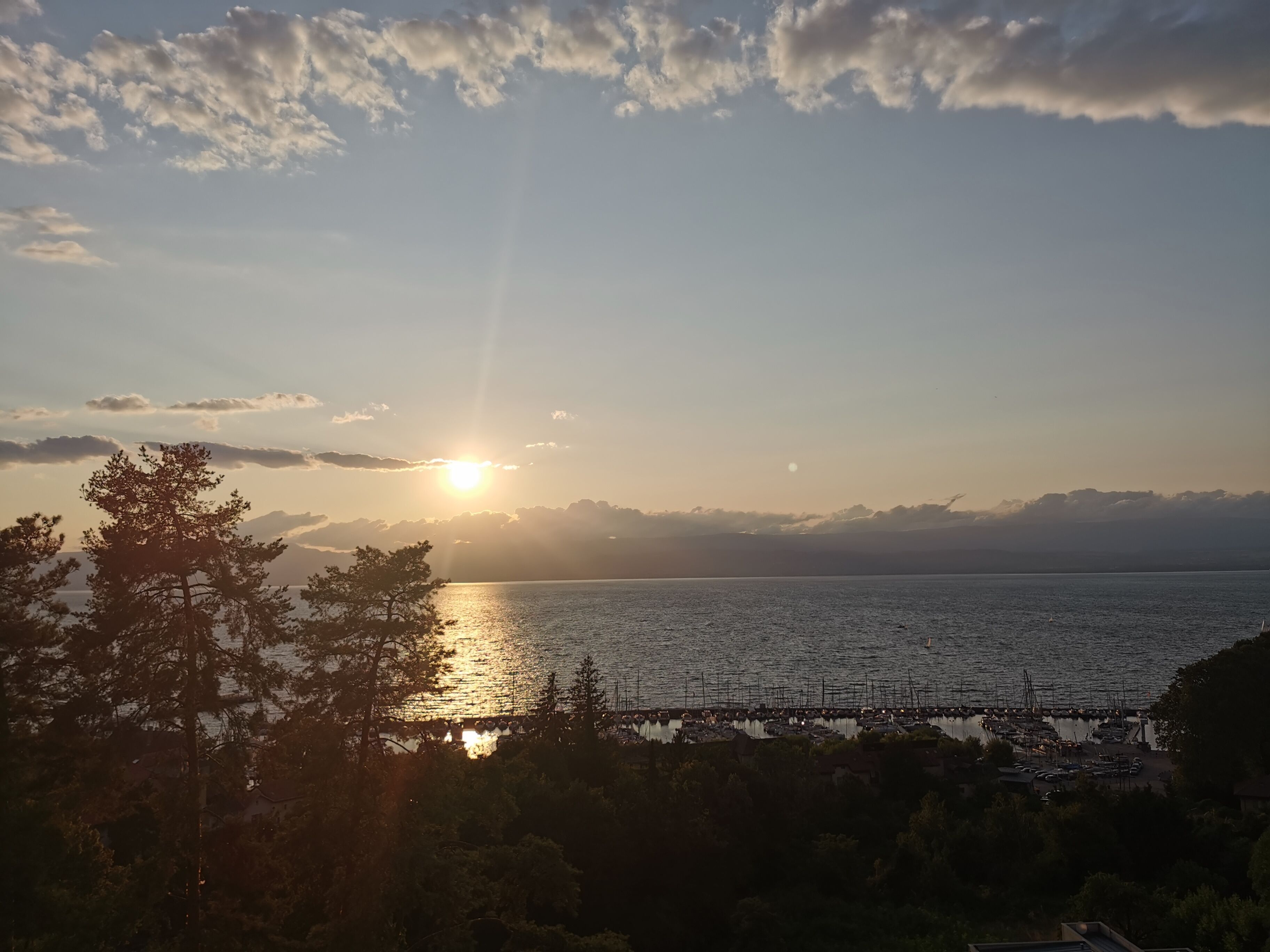 A coastal sunset view with a marina and docked boats.