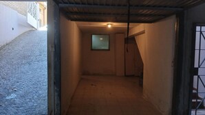 A narrow corridor with a tiled floor, a small window, and a door leading to another room.
