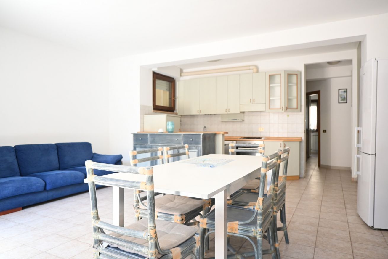 Una cocina moderna con armarios blancos, una mesa de comedor con sillas, un sofá azul y un refrigerador.
