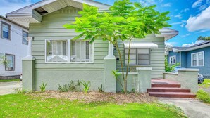A two-story house with a green exterior, white trim, and a small tree in the front yard. - Grill & Porch! Extended Escape, 2 Mi to Ybor City (Tampa)