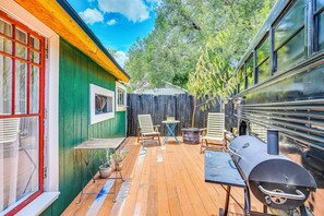 A wooden deck with outdoor seating, a barbecue grill, and a green building with a window. - Grill & Porch! Extended Escape, 2 Mi to Ybor City (Tampa)