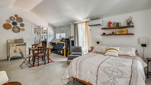 A bedroom with a bed, a desk, a chair, a wardrobe, and shelves with books and decorative items. - Grill & Porch! Extended Escape, 2 Mi to Ybor City (Tampa)