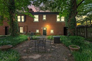 A brick house with a patio, outdoor furniture, and a well-maintained garden.