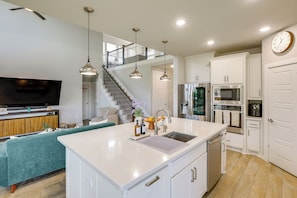 A modern kitchen with a central island, stainless steel appliances, and a staircase leading to an upper level.