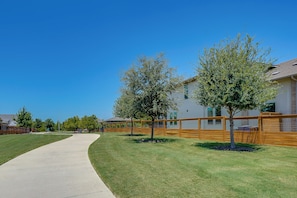 A residential area with a paved walkway, wooden fences, and trees.