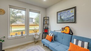 Ein Wohnzimmer mit blauem Sofa, einer Gitarre, einem gerahmten Gemälde und einer Buddha-Statue.