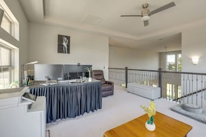 A spacious living area with a ceiling fan, a flat-screen TV, a dining table, and a sofa.