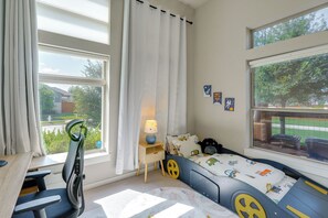 A child's bedroom with a bed, a desk, and a window with curtains. - Easy Airport & I-35 Access: Modern Austin Home (Austin)