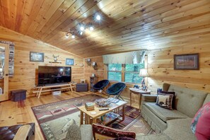 A cozy cabin interior with a wooden ceiling, a television, a fireplace, and a sofa. - Hot Tub & Game Room! Wooded Retreat in Blue Ridge (Blue Ridge)