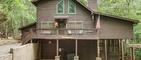 A cabin with a porch, a chimney, and a flag.
