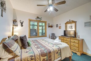 Un dormitorio con cama, cómoda, televisor y diversas decoraciones en las paredes.