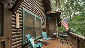 A wooden cabin with a 'WELCOME' sign, a large window, a table with chairs, and an American flag. - Hot Tub & Game Room! Wooded Retreat in Blue Ridge (Blue Ridge)