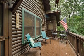 A wooden cabin with a 'WELCOME' sign, a large window, a table with chairs, and an American flag. - Hot Tub & Game Room! Wooded Retreat in Blue Ridge (Blue Ridge)