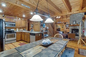 A wooden cabin interior with a kitchen, dining area, and fireplace. - Hot Tub & Game Room! Wooded Retreat in Blue Ridge (Blue Ridge)