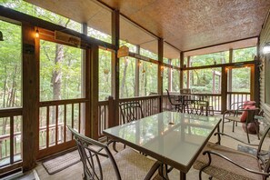 A covered outdoor dining area with a table and chairs, large windows, and a 'Welcome' sign. - Hot Tub & Game Room! Wooded Retreat in Blue Ridge (Blue Ridge)