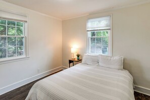 A bedroom with a bed, two windows, a nightstand with a lamp, and a potted plant. - 3 Mi to Dtwn Columbia! Charming Home w/ Yard (Columbia)