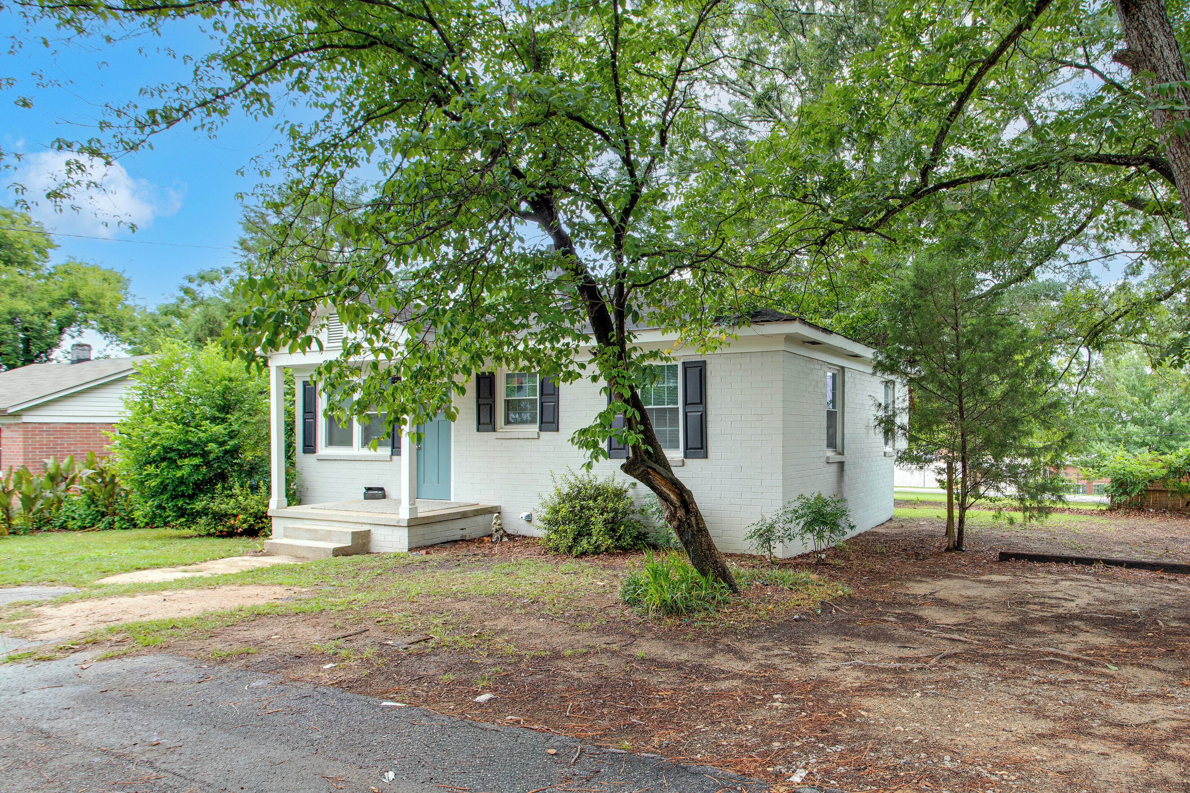 A single-story house with a front porch, a small front yard, and a tree in front.
