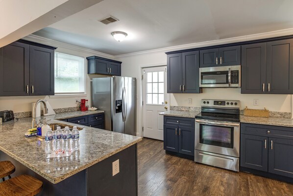 A modern kitchen with dark cabinets, stainless steel appliances, and a granite countertop.