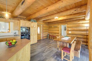 Ein Holzblockhaus-Interieur mit Küche, Essbereich und einer großen Holzbalkendecke.