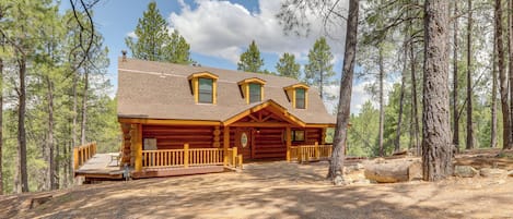 A log cabin with a porch, a chimney, and a deck.