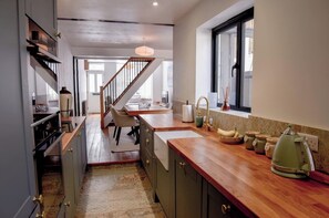 A kitchen with a wooden countertop, a sink, and a window. - Relax at Pebble House for a seaside break. (Whitstable)