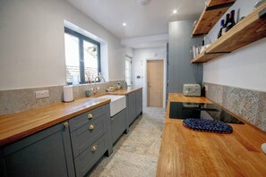 A kitchen with a wooden countertop, a sink, and a window. - Relax at Pebble House for a seaside break. (Whitstable)