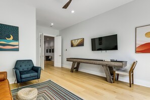 Ein modernes Wohnzimmer mit einer Couch, einem Couchtisch, einem an der Wand montierten Flachbildfernseher und einer Wandpaneele aus Holz.