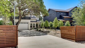 A modern two-story house with a covered patio, a driveway, and a wooden fence. - Walk to Shore! Family-friendly Canyon Lake Retreat (Canyon Lake)