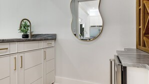 A modern kitchen with white cabinetry, a marble countertop, and a large mirror with a gold frame. - Walk to Shore! Family-friendly Canyon Lake Retreat (Canyon Lake)