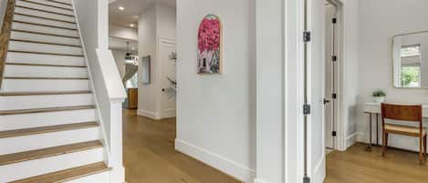 Una escalera con escalones de madera y paredes blancas que conduce a una habitación con un escritorio y una silla.